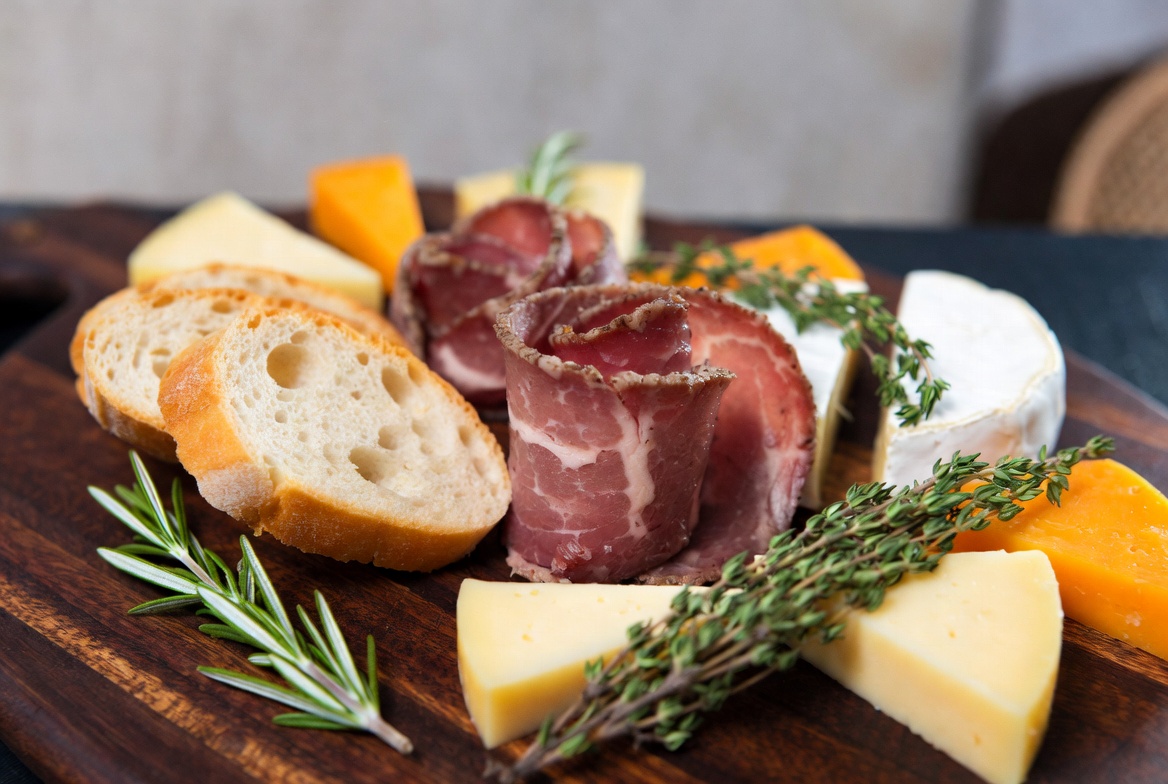 Cured beef, artisan cheese, and fresh bread on a wooden board